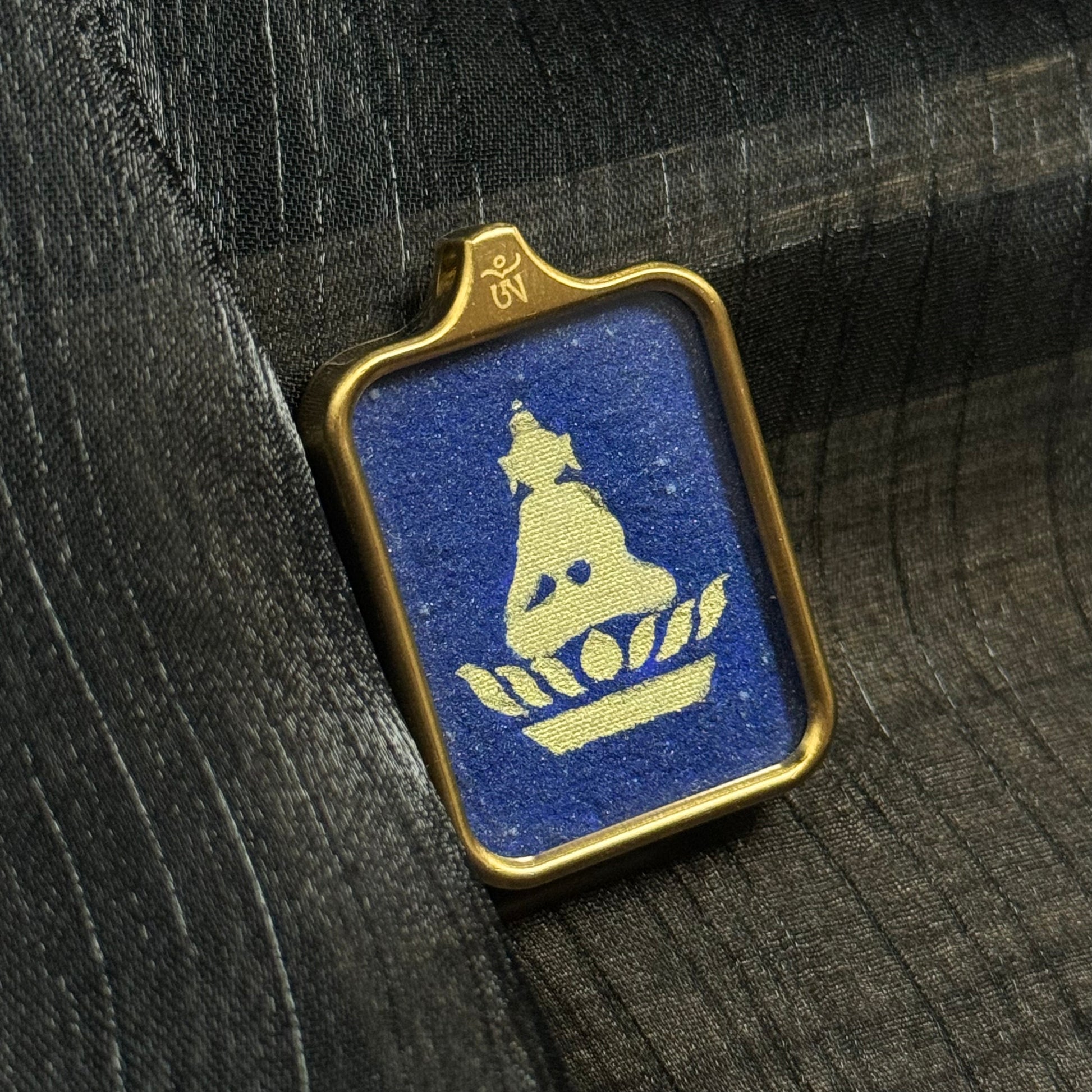 Close view of a Formless Buddha miniature thangka pendant painted with pure gold powder over coarse lapis lazuli mineral pigments, framed in a protective metal pendant case.