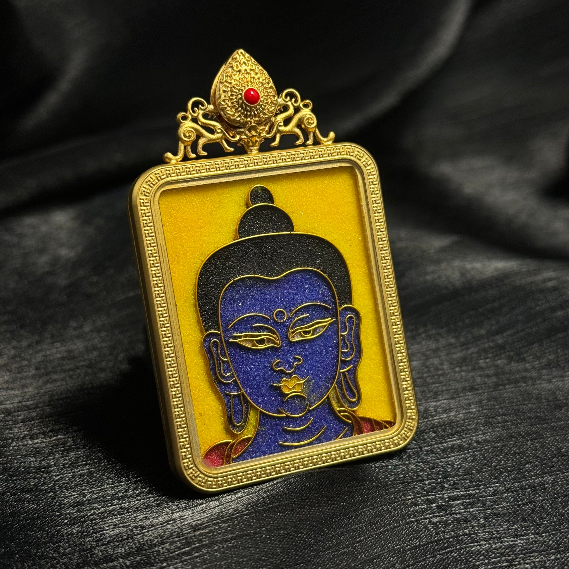 Detailed view of Medicine Buddha cloisonné enamel mini thangka pendant highlighting Buddha face iconography, layered enamel colors, and ornate gold-plated frame