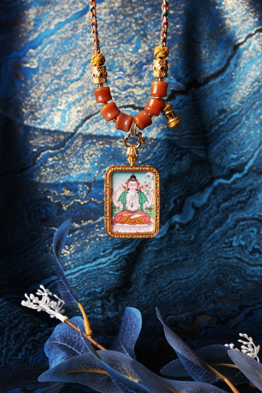 Hanging display of Four-Armed Avalokiteshvara mini thangka pendant showing the rectangular metal bezel, pendant connector hardware, and layered bead sections on the necklace
