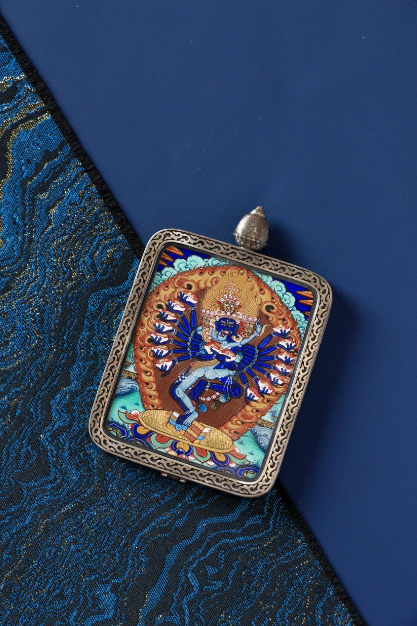 Close-up of the Hevajra mini thangka pendant highlighting fine hand-painted lines, Rebgong-style iconographic proportions, and layered mineral pigment coloring inside a pure silver pendant frame.
