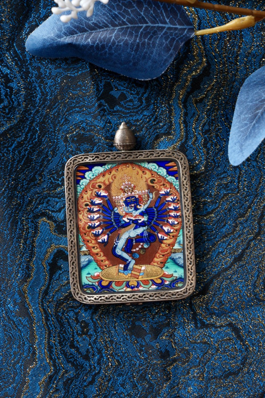 Hevajra mini thangka pendant shown in a lifestyle setting as a portable Tibetan Buddhist art piece, suitable for collectors and for use on a travel altar, meditation space, or personal shrine.