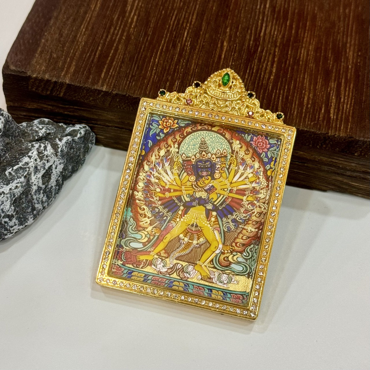 Angled view of Kalachakra double-sided thangka pendant, showing reflective titanium steel jewelry case, crystal detailing, and preserved hand-painted surface.