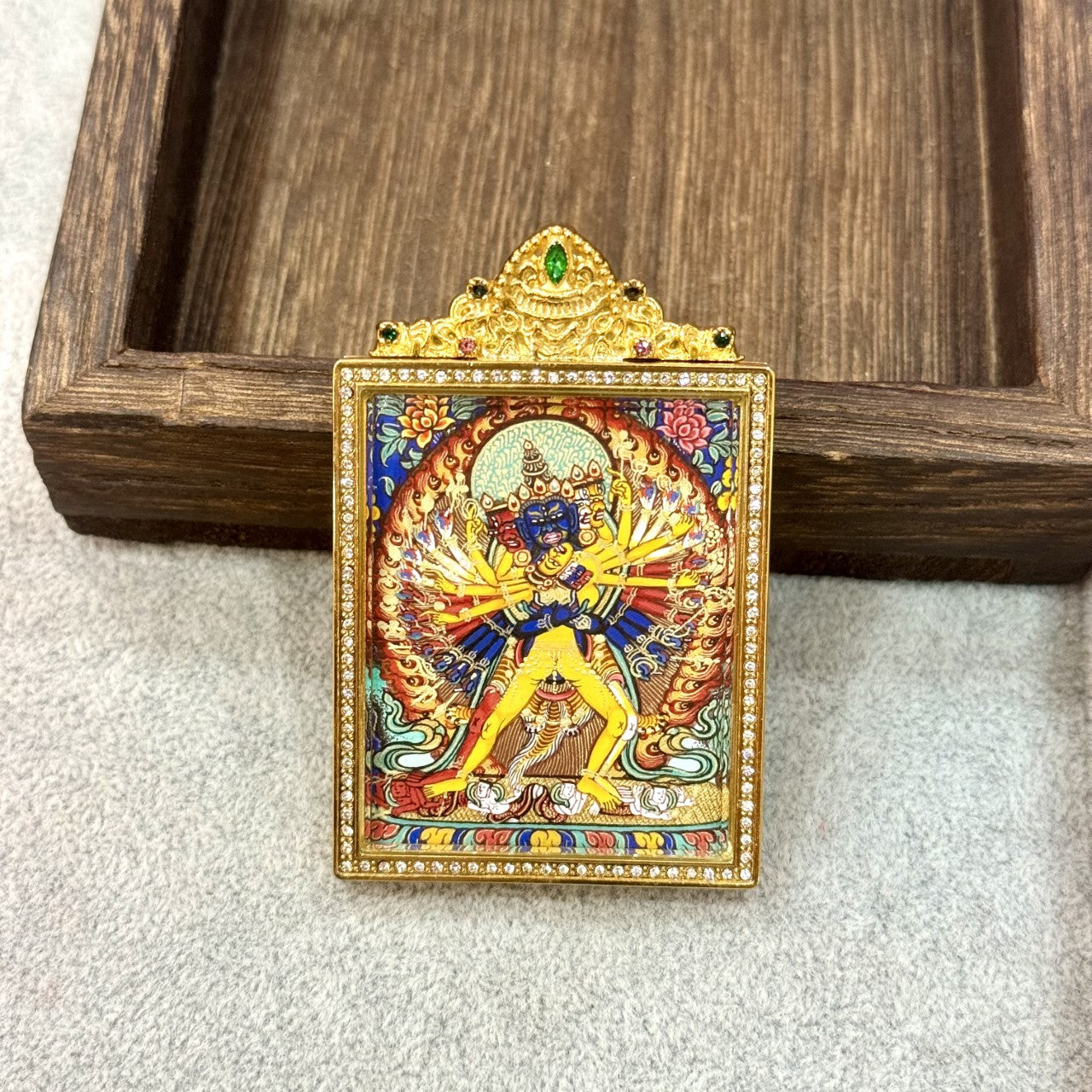 Close-up view of Kalachakra thangka pendant showing layered mineral pigments, fine line work, vivid color transitions, and decorative gold-toned frame craftsmanship.