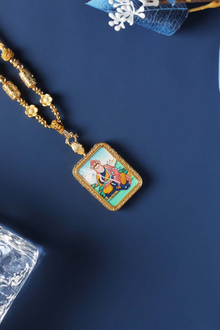 Angled view of Ksitigarbha mini thangka pendant showing seated bodhisattva figure, mineral pigment layers, and gold-tone frame details