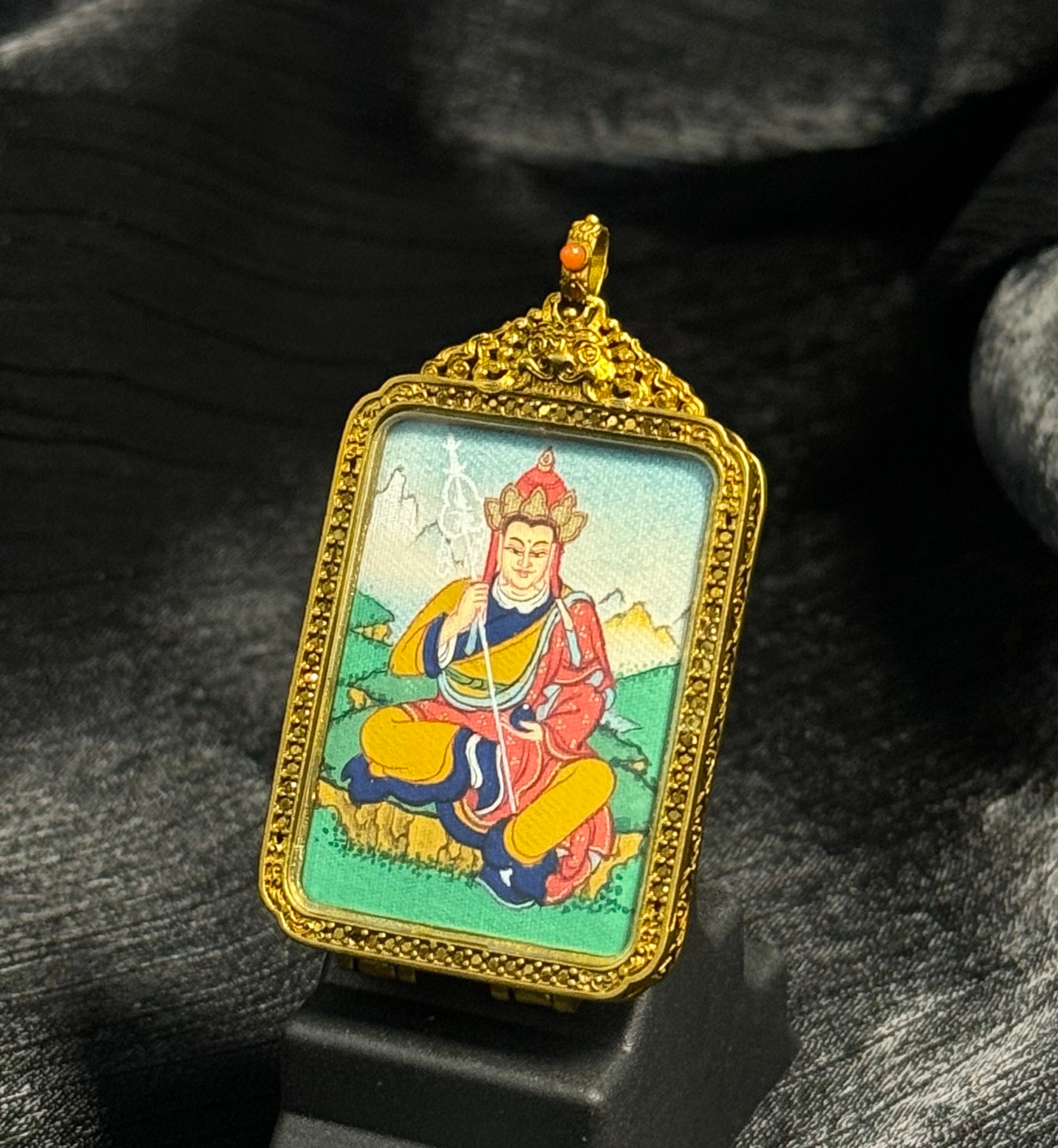 Detailed angled view of Ksitigarbha Bodhisattva miniature thangka pendant mounted in an ornate Tibetan copper case