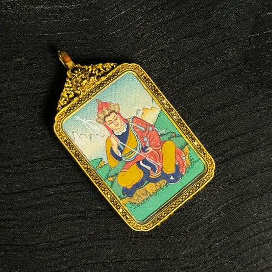 Angled view of hand-painted Ksitigarbha Bodhisattva miniature thangka pendant showing detailed mineral pigment painting and ornate copper frame