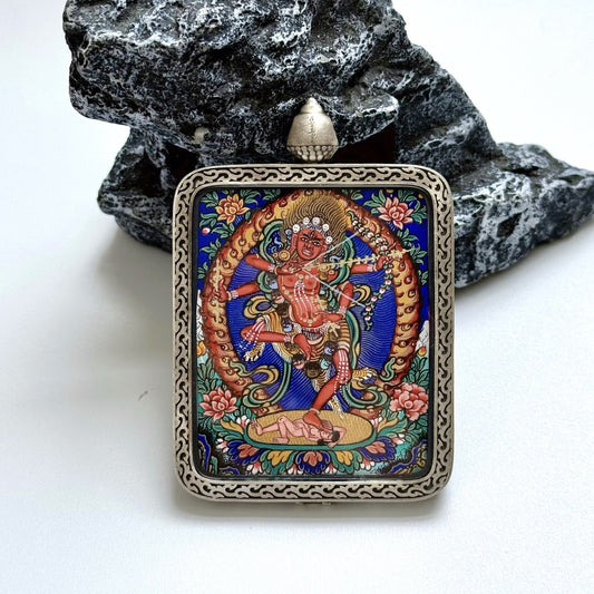 Front view of Kurukulla mini thangka pendant highlighting the hand-painted deity figure, flame-like halo ring, lotus base, and intricate silver frame patterning on the Dunhuang Nine-Color Deer case