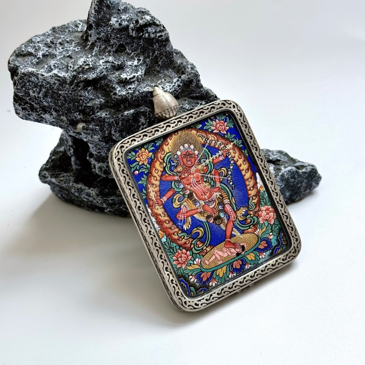 Full view of Kurukulla mini thangka pendant showing compact portable format, bright mineral pigment colors, and the silver protective case with decorative border and top bail