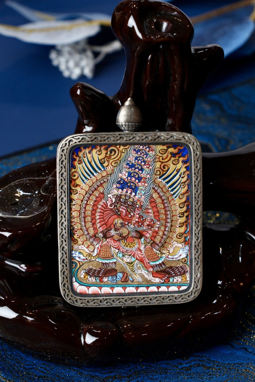 Maha Heruka mini thangka pendant displayed for devotional and collectible presentation, highlighting sculptural form and vivid color composition