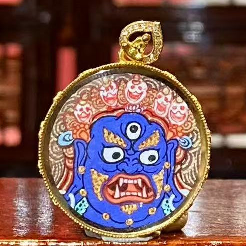 Front view of round Mahakala thangka pendant hand-painted in 18K gold, Rebgong style, symbolizing destruction of obstacles and wisdom growth