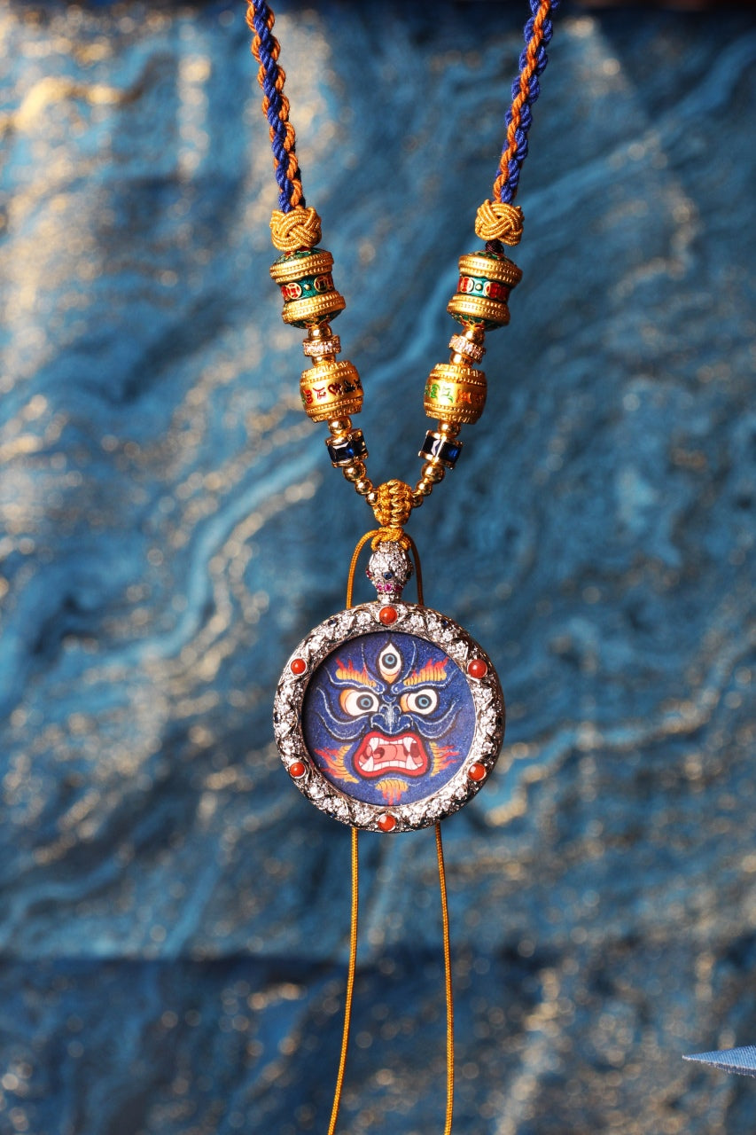 Close-up view of a Mahakala protector deity face, hand-painted with layered mineral pigments, emphasizing wide eyes, fierce expression, and textured lapis-toned surface.

