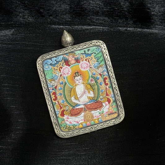 Angled view of Mahasthamaprapta Bodhisattva thangka pendant showing mineral pigment detailing, layered halo, lotus base, and engraved silver frame with top loop.