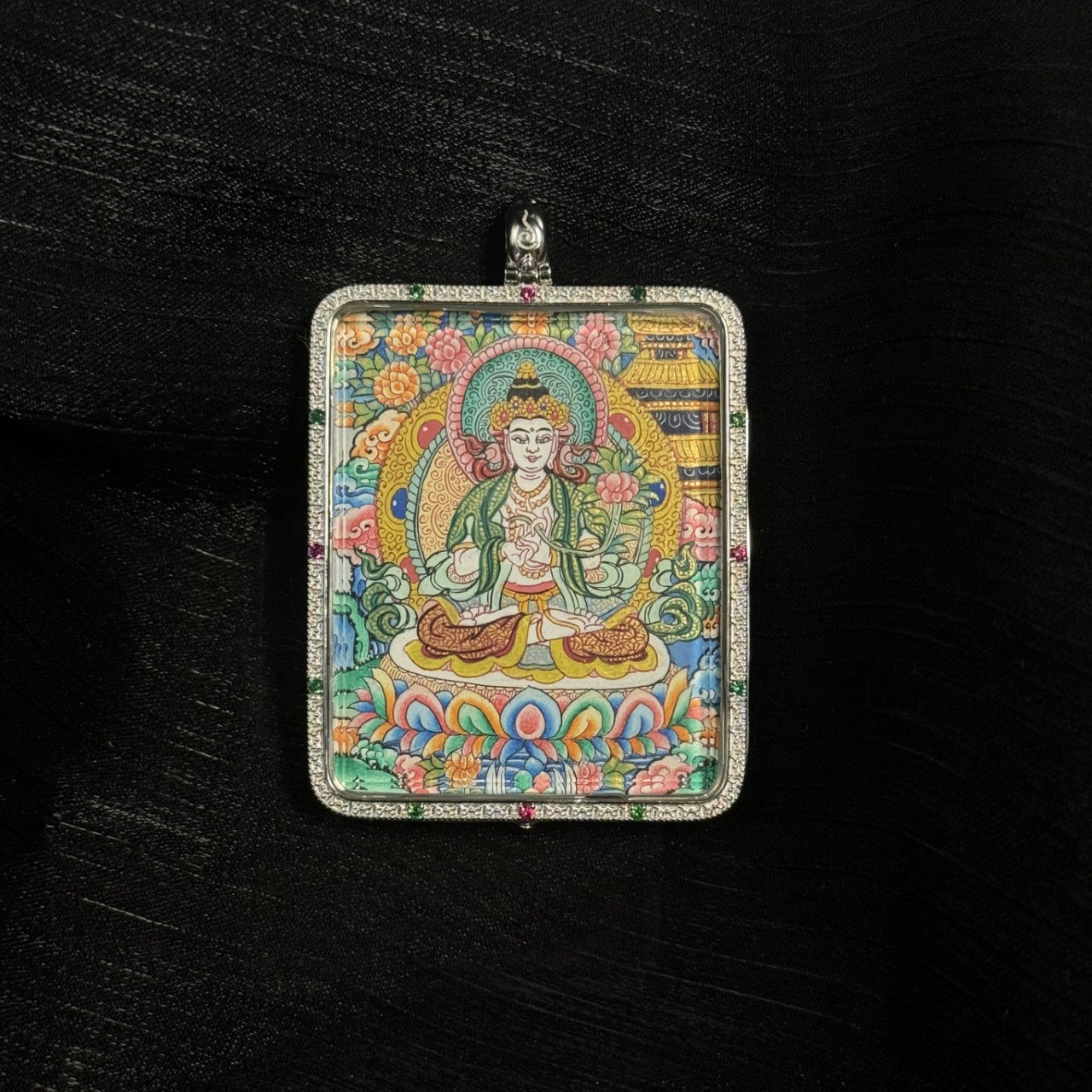 Front view of the Mahasthamaprapta Bodhisattva mini thangka pendant showing the bodhisattva seated on a multicolored lotus base with halo, floral background, and traditional Tibetan temple motifs.