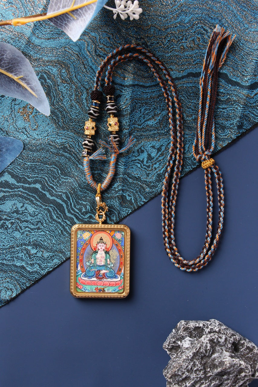 Angled view of Mahasthamaprapta Bodhisattva mini thangka pendant in a titanium steel case with hand-painted mineral pigment artwork and braided cord.