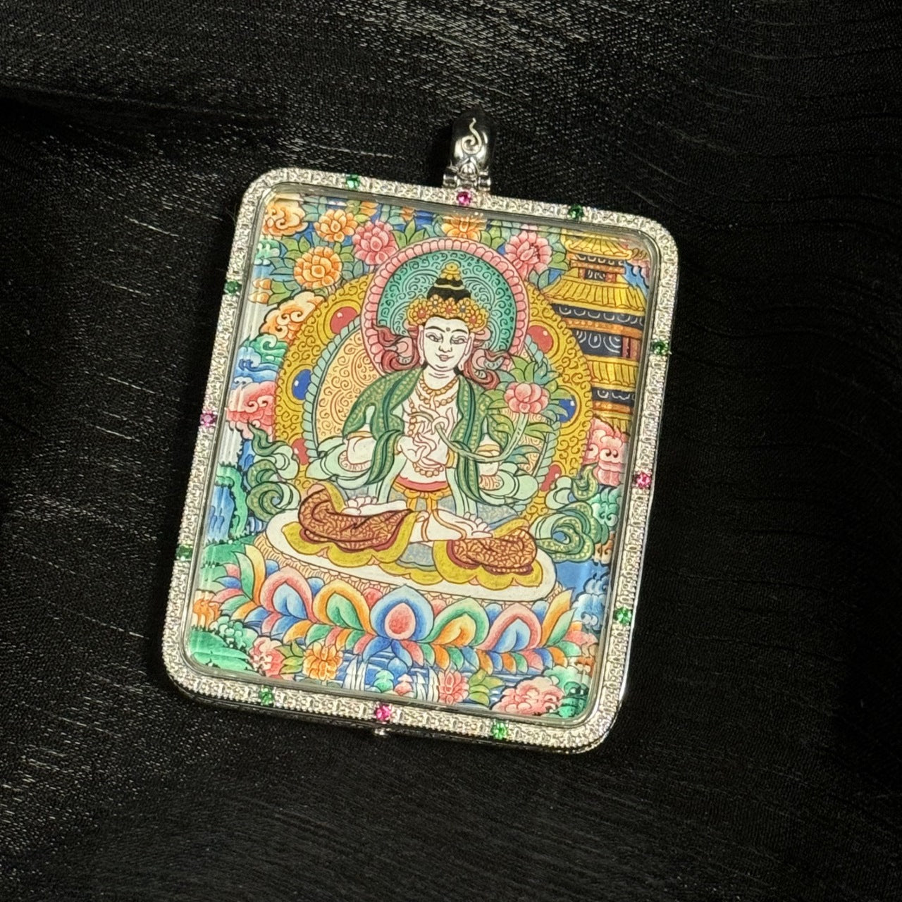 Detailed close-up of the Mahasthamaprapta Bodhisattva mini thangka pendant highlighting mineral pigment painting, lotus throne, halo ornament, and intricate Tibetan floral patterns inside a square silver pendant case.