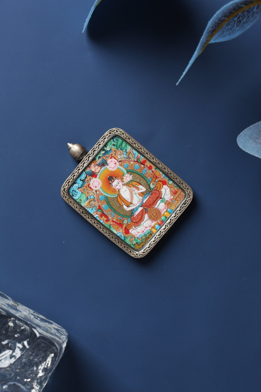 Angled view of a Mahasthamaprapta Bodhisattva mini thangka pendant featuring clean composition and strong lines, in a silver gawu-style case.