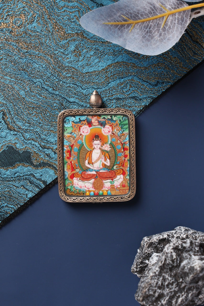 Lifestyle view of a Mahasthamaprapta Bodhisattva mini thangka card pendant, portable Tibetan devotional art in Qigang style with a silver gawu case.