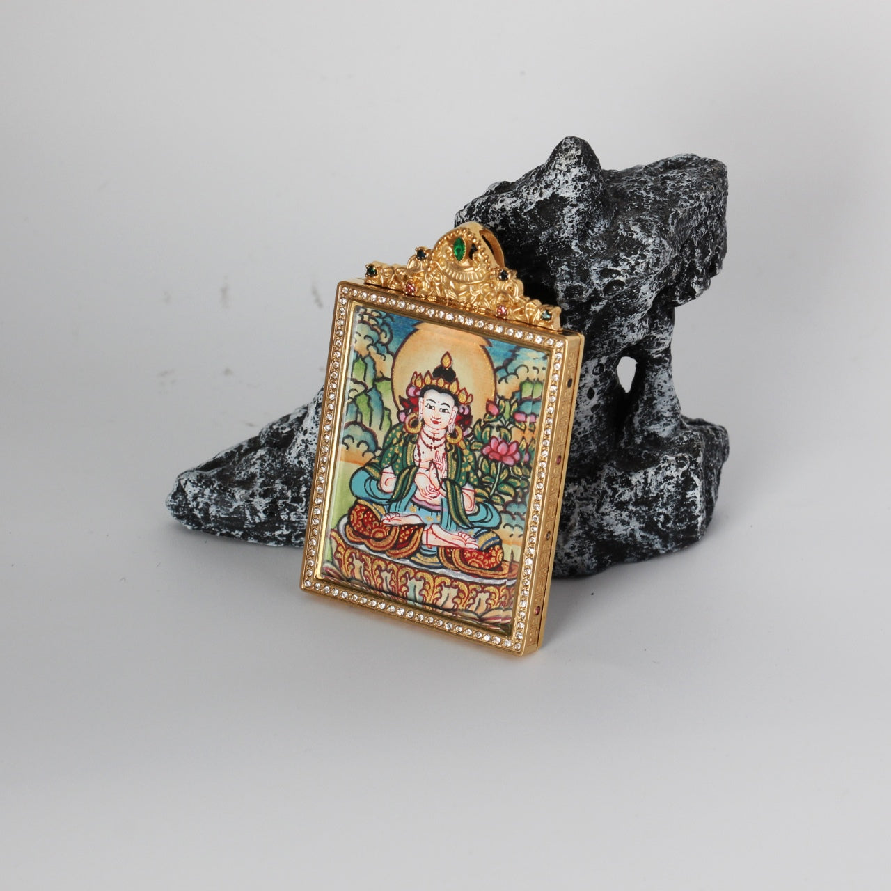 Side-angled photo of Mahasthamaprapta Bodhisattva mini thangka pendant showing the gold-tone titanium steel case profile, crystal border around the front window, and the hand-painted bodhisattva image inside.
