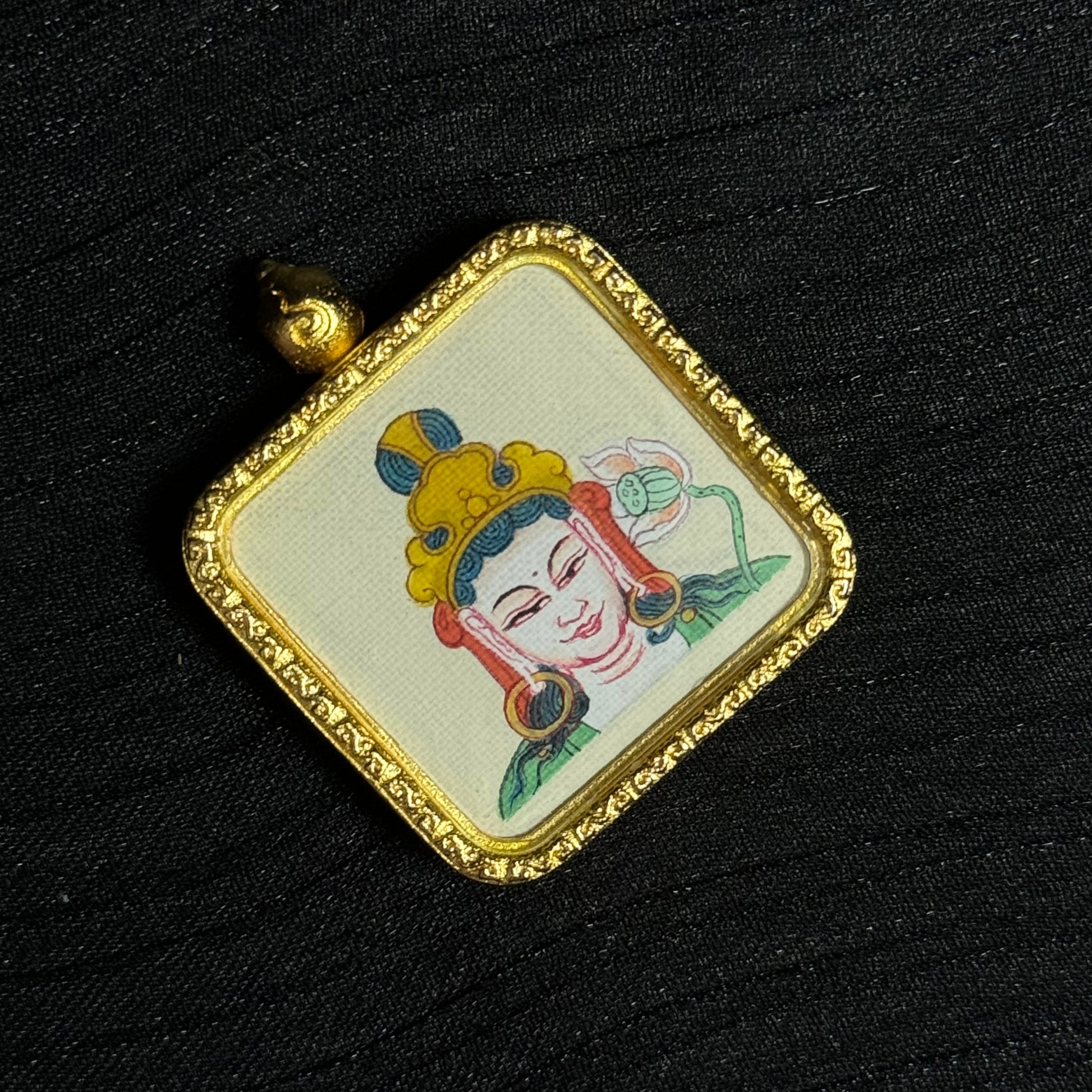 Detailed view of Mahasthamaprapta Bodhisattva miniature thangka painting with lotus motif and traditional Tibetan iconography mounted in a square gold-toned pendant frame.