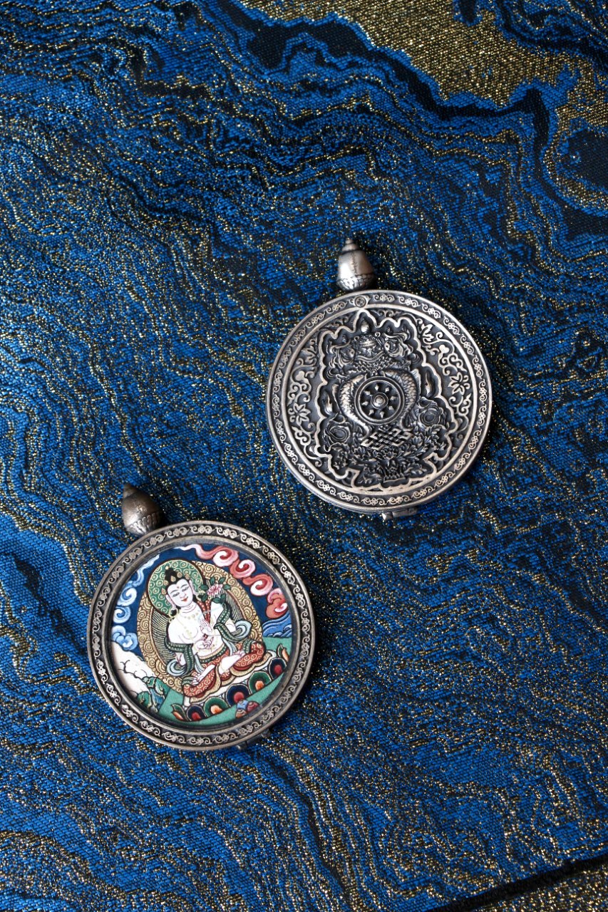 Hand-painted Mahasthamaprapta Bodhisattva thangka pendant in Rebgong cloud-background style, shown with painted front and engraved 925 silver back on blue textile background