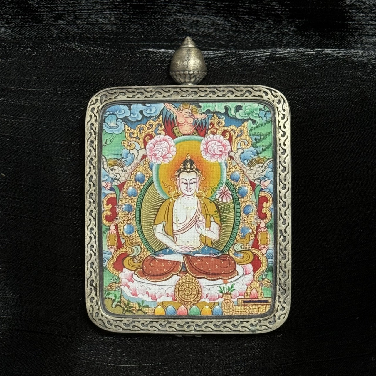Close-up front view of Mahasthamaprapta Bodhisattva Tibetan Mianthang mini thangka pendant, featuring lotus throne, circular halo, floral motifs, symbolic offerings, and engraved silver border.