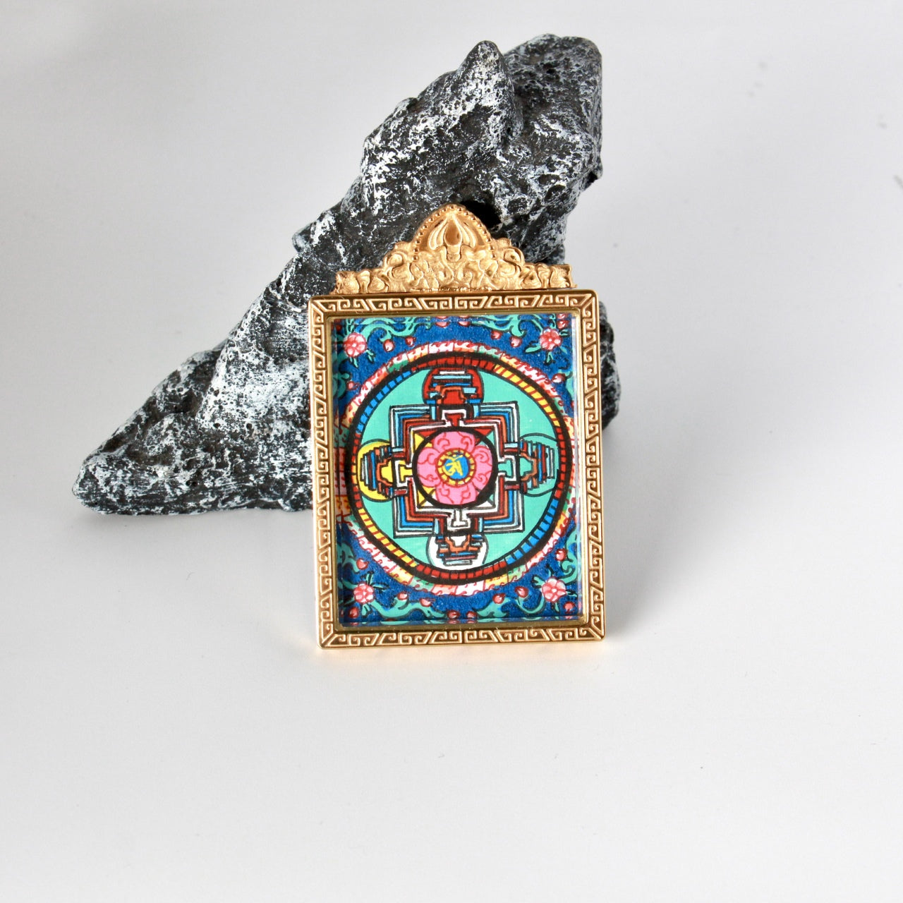 Back view of double-sided mini thangka pendant featuring a hand-painted mandala design, framed in a gold-tone titanium steel case with geometric border pattern