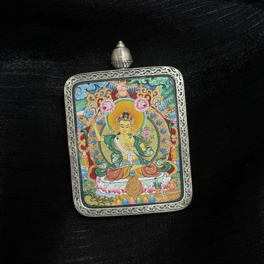 Angled view of Manjushri Bodhisattva thangka pendant showing raised wisdom sword, lotus support, circular halo, layered mineral pigment colors, and engraved silver frame with top loop
