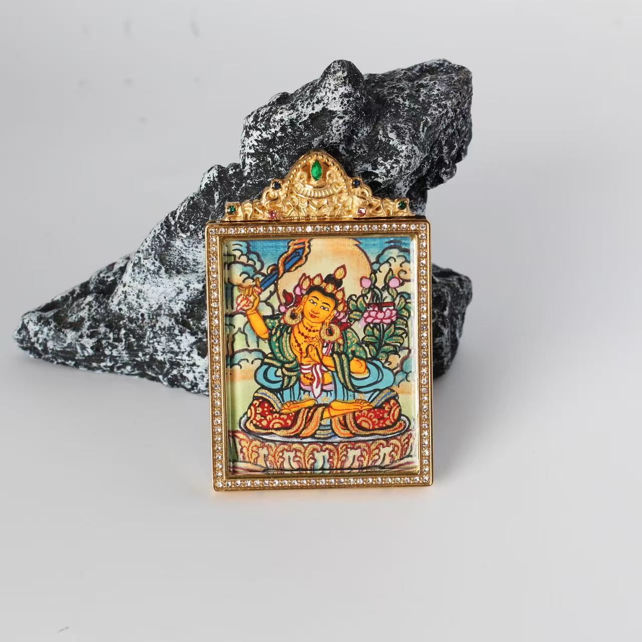 Front view of the Manjushri Bodhisattva mini Thangka pendant featuring a jeweled gold-tone double-sided titanium steel case, crystal border detailing, and a central painted image of Manjushri holding a flaming sword.