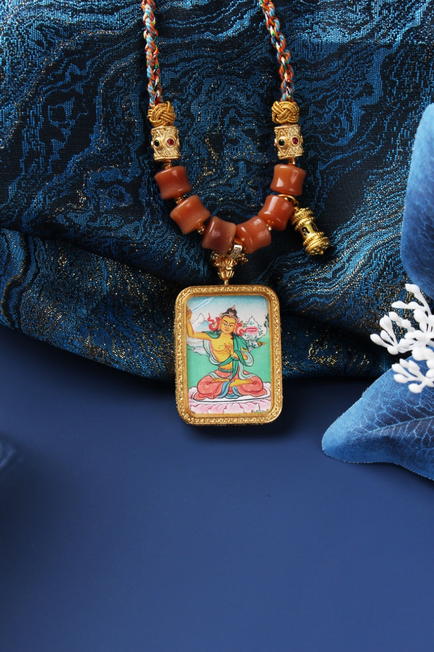 Front view of Manjushri Bodhisattva mini thangka pendant highlighting the hand-painted image, textured rectangular metal frame, and symmetrical bead arrangement on the necklace