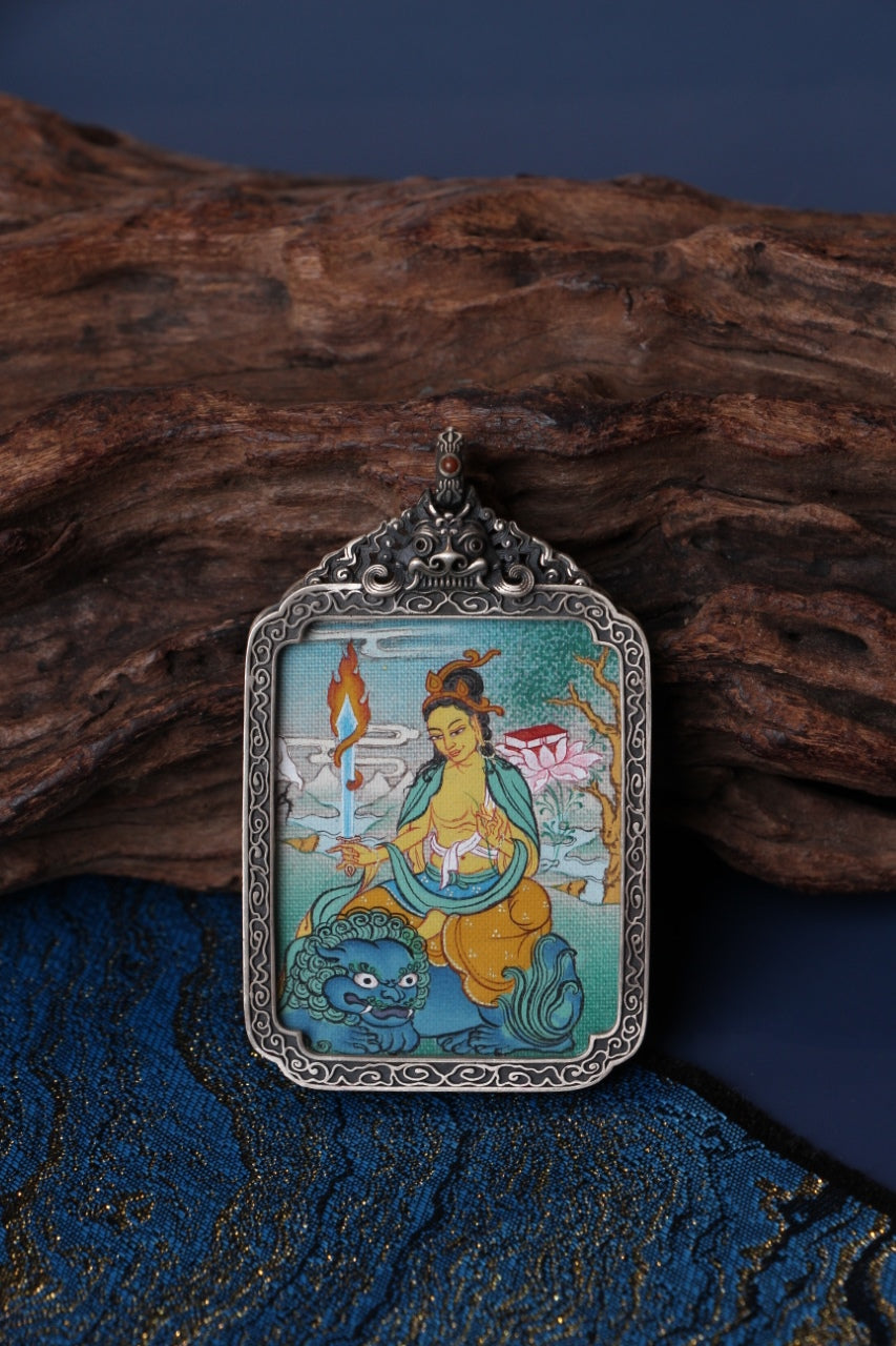 Close-up detail of Manjushri Bodhisattva mini thangka pendant, showing traditional Tibetan hand-painted mineral pigment artwork inside a vintage silver case