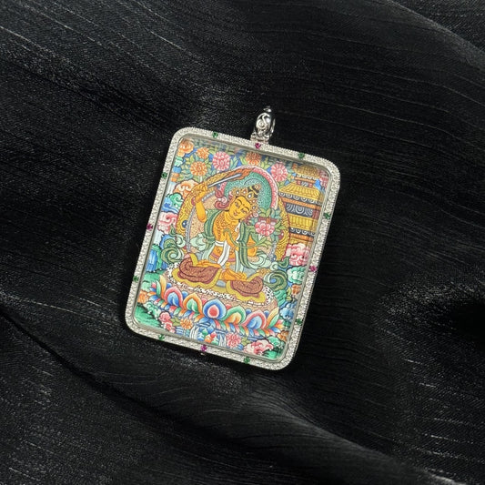 Hand-painted Manjushri Bodhisattva miniature thangka pendant featuring the wisdom deity seated on a lotus throne with vibrant mineral pigments and a decorative silver frame.
