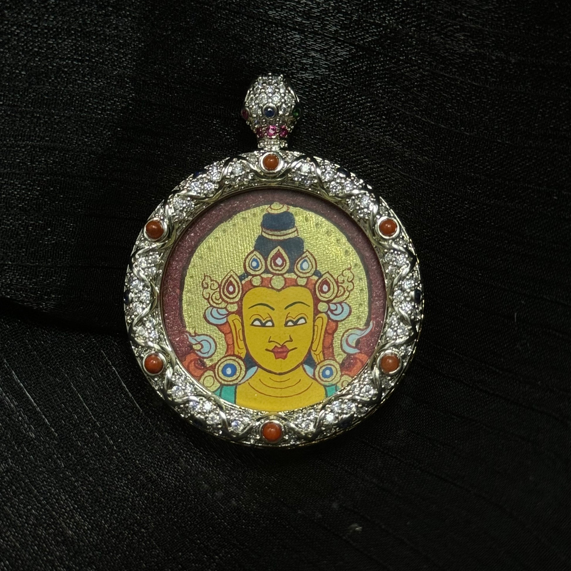 Round Manjushri Bodhisattva mini thangka pendant with jeweled copper frame, hand-painted mineral pigment portrait on red background in Rebgong Tibetan style.