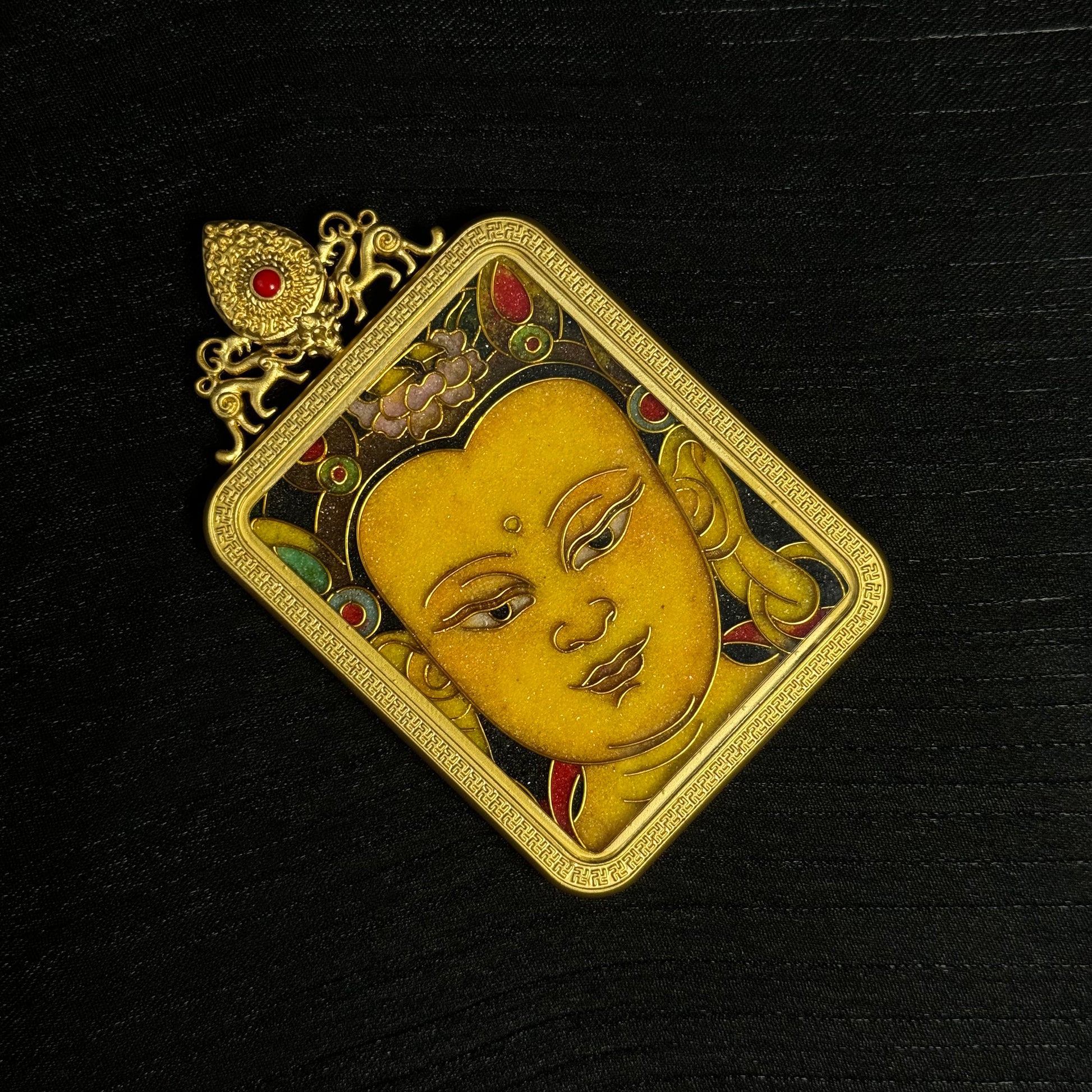 Top view of a Manjushri cloisonné enamel mini thangka pendant featuring the gold-plated decorative crown element and detailed enamel patterns.