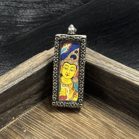 Front view of a Manjushri mini thangka pendant featuring a hand-painted yellow Manjushri face with detailed crown patterns, blue upper background with flame motif, and an ornate raised metal border.