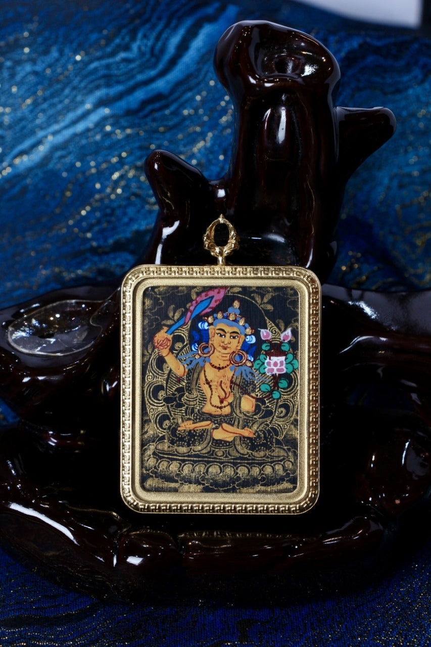 Front view of a Manjushri Bodhisattva mini thangka pendant in Nepalese black-gold style, 3.5×4.5 cm, set in a titanium steel frame, displayed on a dark sculpture.