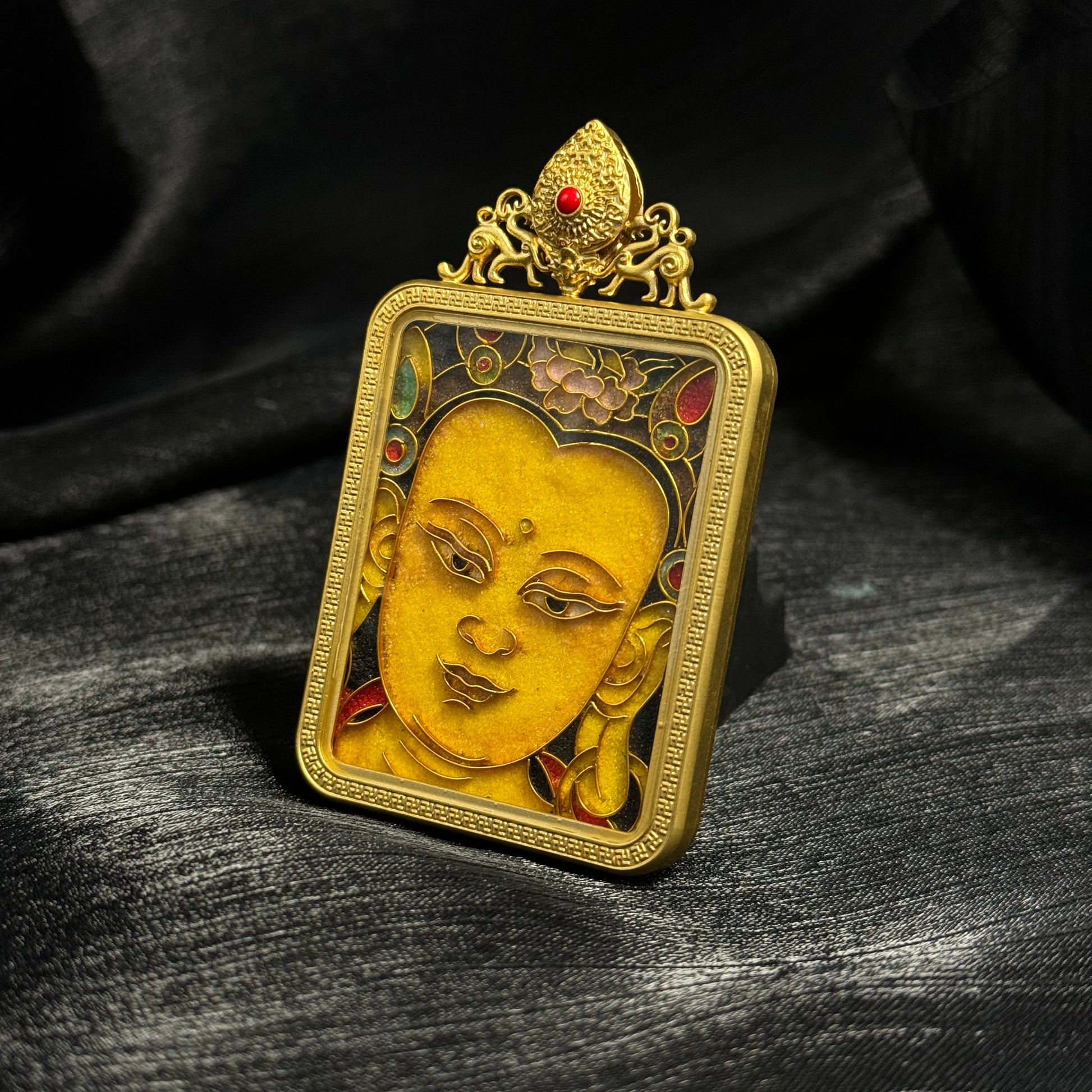 Side-angle detail of a Manjushri Bodhisattva mini thangka pendant showing the thickness of the gold-plated copper case and cloisonné enamel craftsmanship.