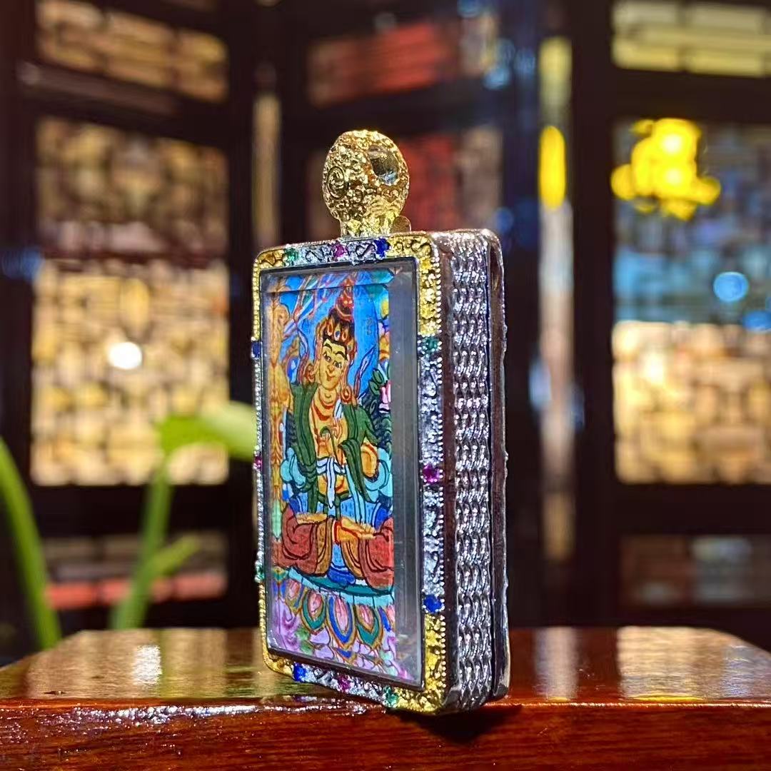 Side view of a hand-painted Manjushri Bodhisattva mini thangka pendant showing the detailed gold-plated copper Gau box frame
