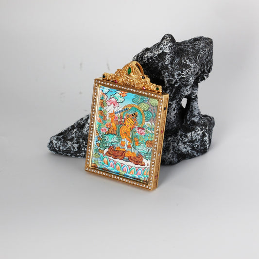 Angled side view of a Manjushri thangka pendant with a jeweled gold-tone frame and double-sided titanium steel case, photographed on a black stone prop.