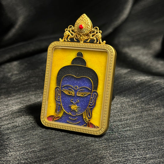 
Angled close-up of Medicine Buddha cloisonné enamel pendant showing gold wire cloisonné lines, blue enamel Buddha face, and gold-plated copper protective frame