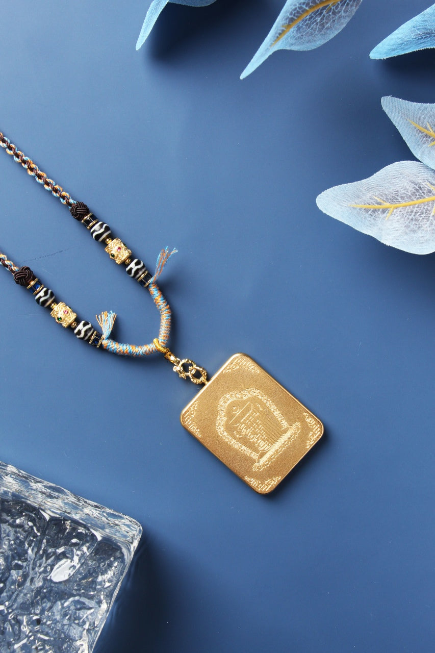 Back view of the mini thangka pendant highlighting the titanium steel case back plate with embossed Tibetan-style motif, engraved corner accents, matte texture finish, and the top bail and clasp connection.