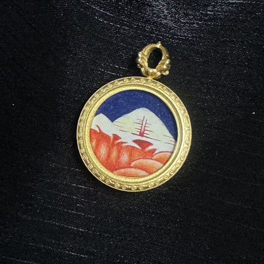 Front view of Mount Kailash mini thangka pendant, hand-painted snow mountain with golden sunlight tones, deep blue sky background, copper case with engraved border