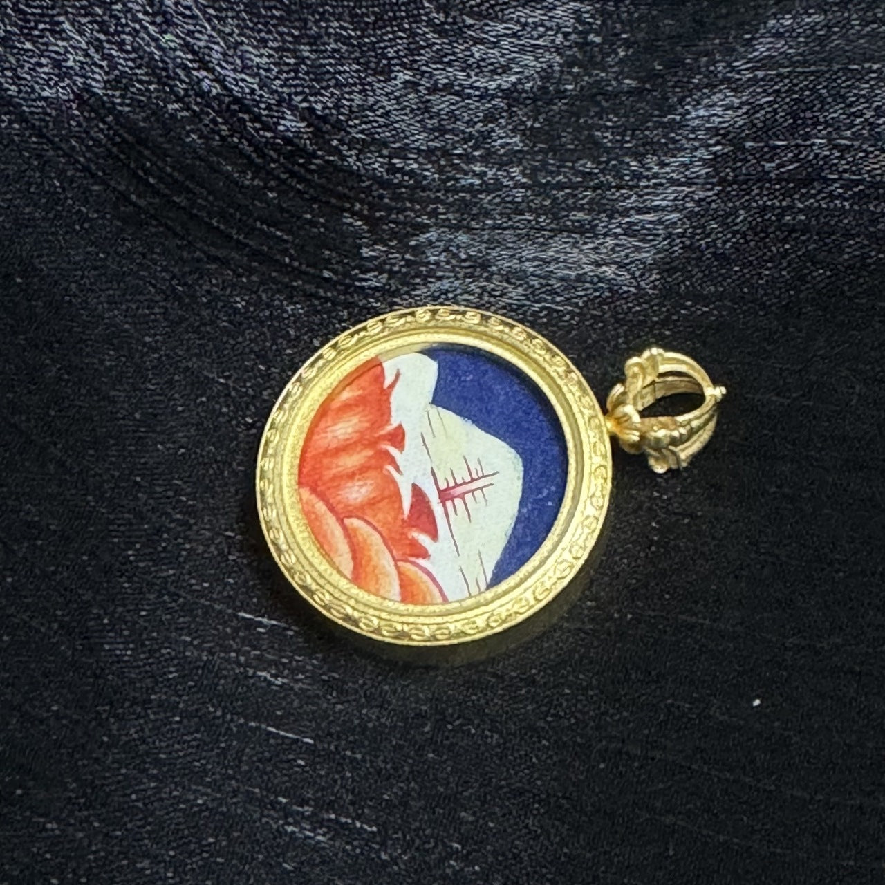 Side angle of Mount Kailash mini thangka pendant showing copper case profile, engraved gold-tone rim, and compact round pendant format