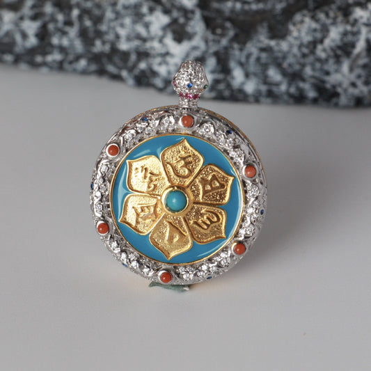 Back view of the Zaki Lhamo mini thangka pendant featuring a raised mantra motif, blue enamel ground, and detailed metal inlay around the circular frame.