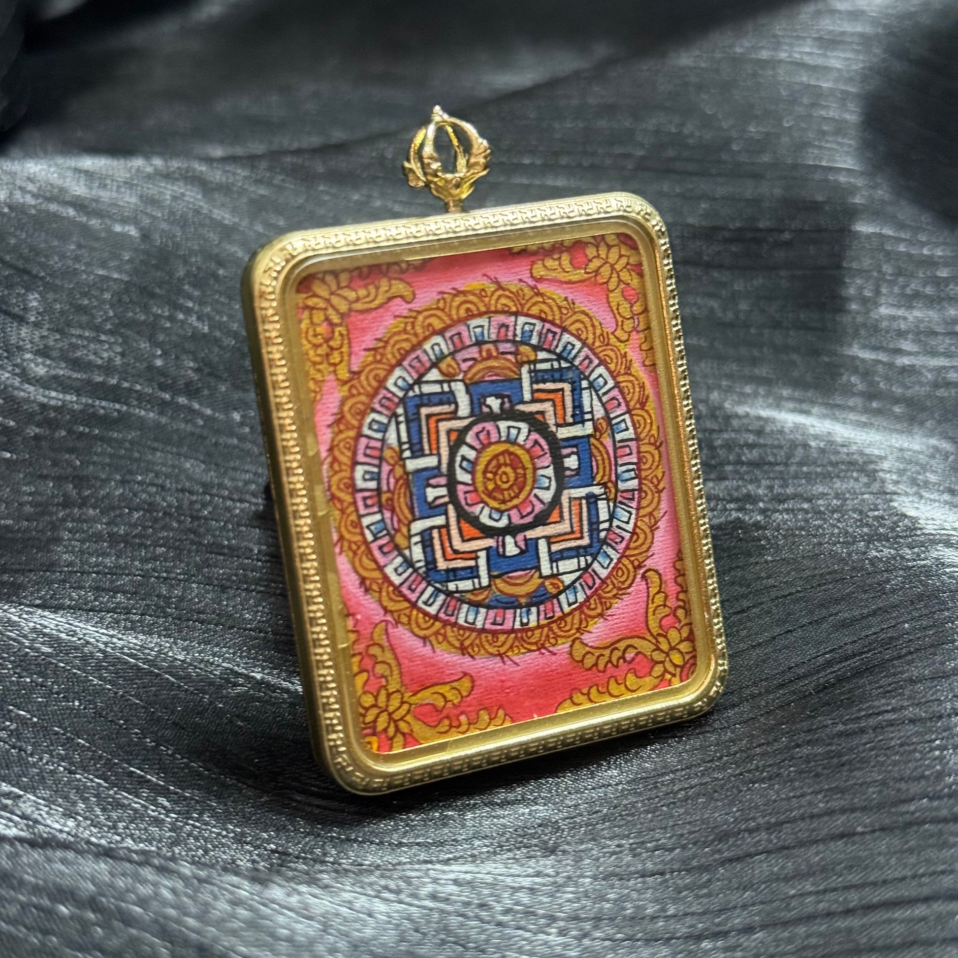 Angled view of a hand-painted mandala mini thangka pendant showing detailed Buddhist sacred geometry and colorful Himalayan thangka patterns.