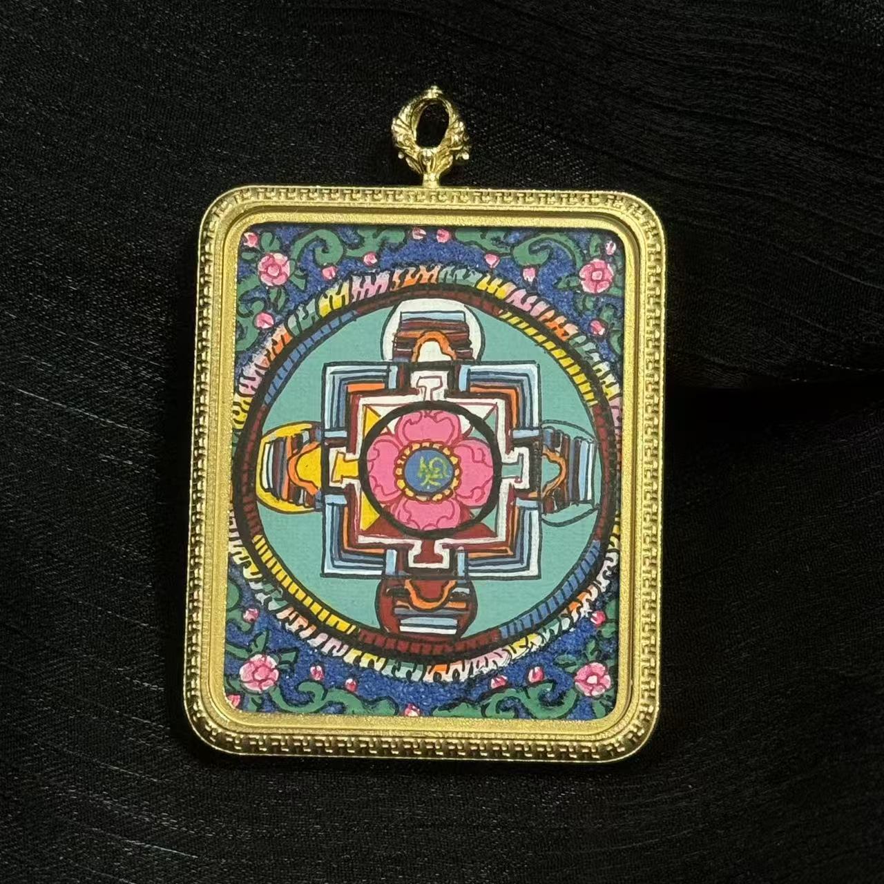 Close front view of Nepal-style mandala thangka pendant featuring colorful sacred geometry design framed in a durable titanium steel case