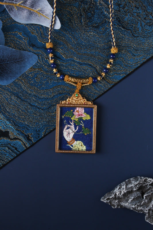 Rectangular White Tara hand thangka pendant on a necklace, deep blue painted background, gold-tone jeweled frame with ornate crown top, blue beads and braided cord.