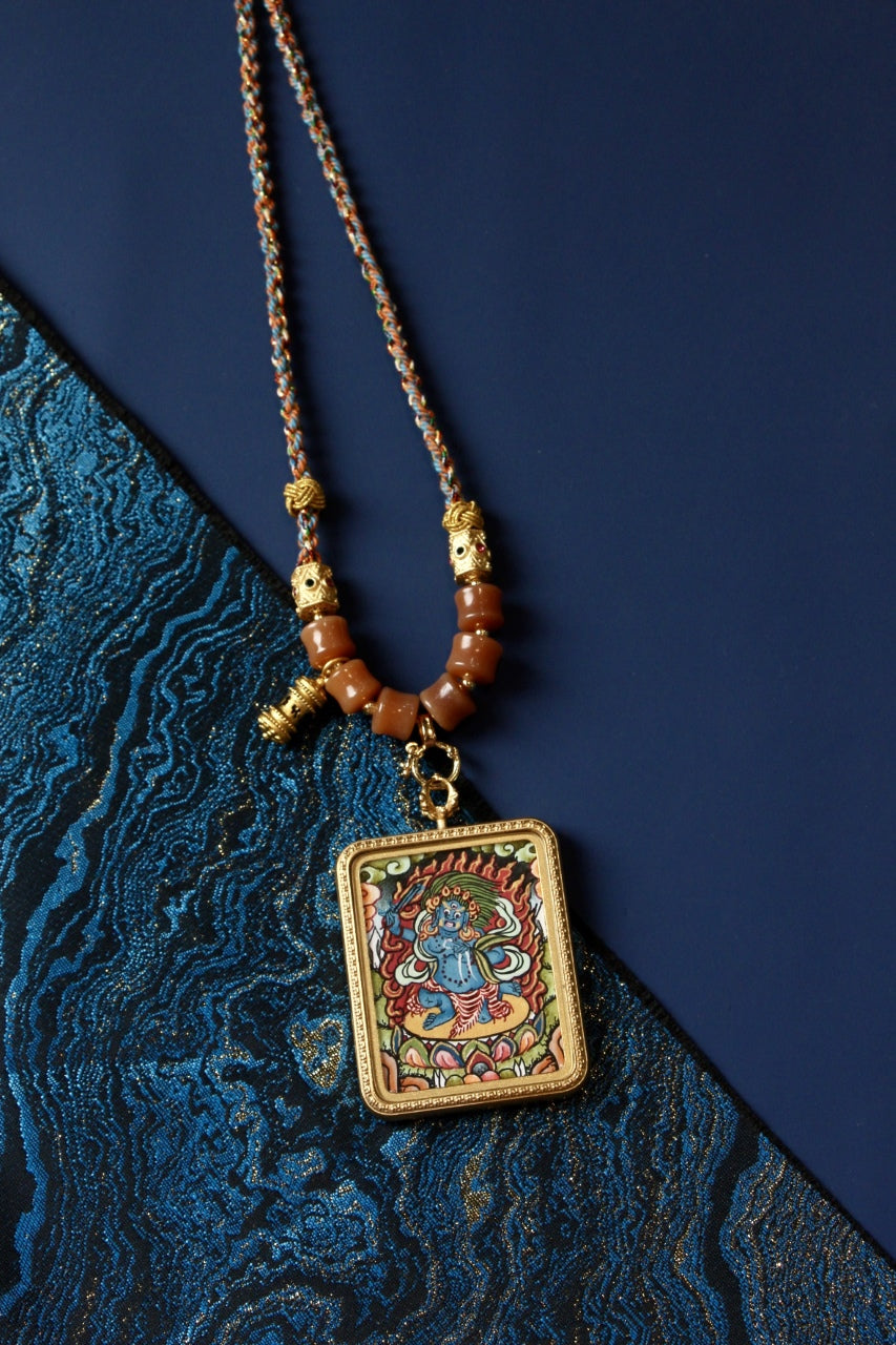 Hand-painted Nepalese color thangka pendant depicting Acalanatha (Fudo Myo-o), the Immovable Wisdom King, framed in titanium steel, symbolizing courage, discipline, and obstacle-removal.