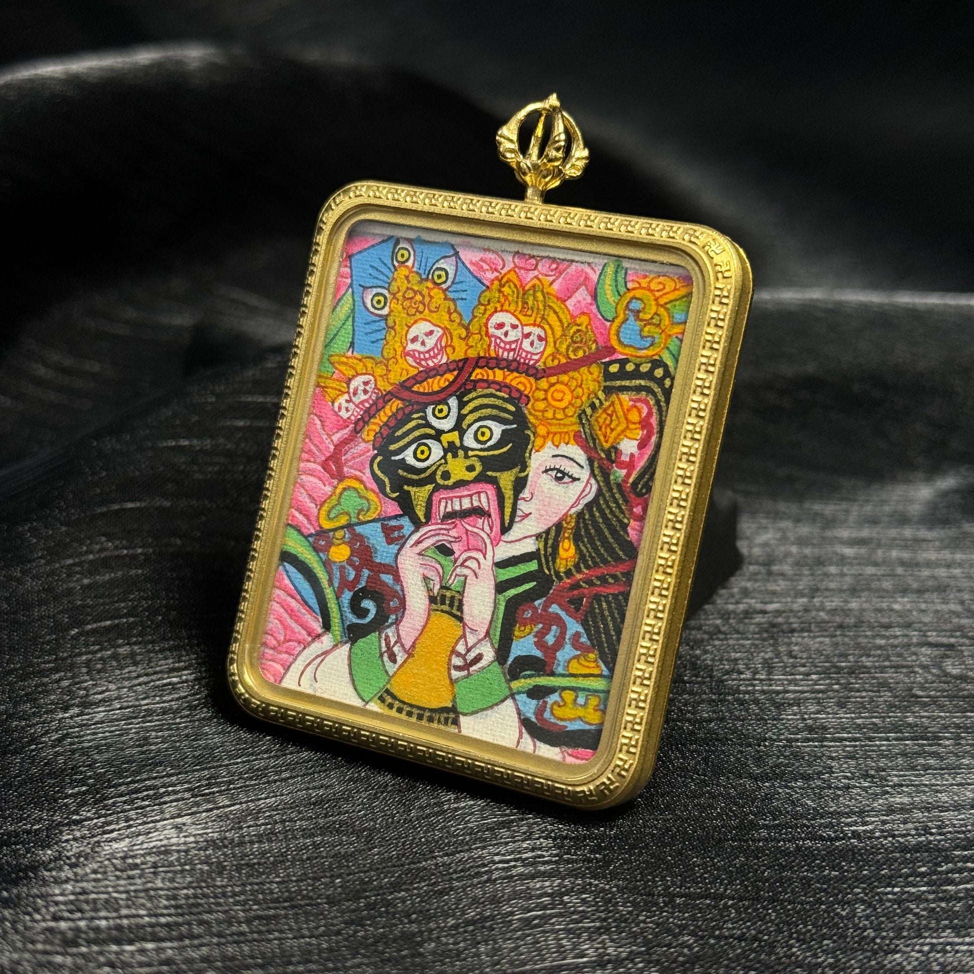 Angled view of Zaki Lhamo mini thangka pendant showing gold pendant frame, vibrant Nepalese color thangka painting, and intricate decorative border.