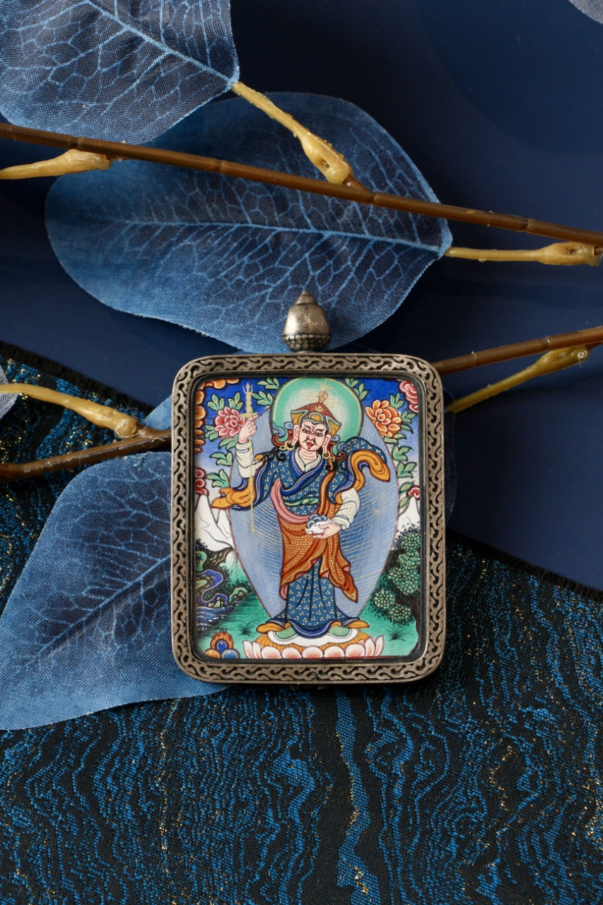Padmasambhava standing form mini thangka pendant displayed with decorative leaves and branches, highlighting the silver gawu-style pendant frame