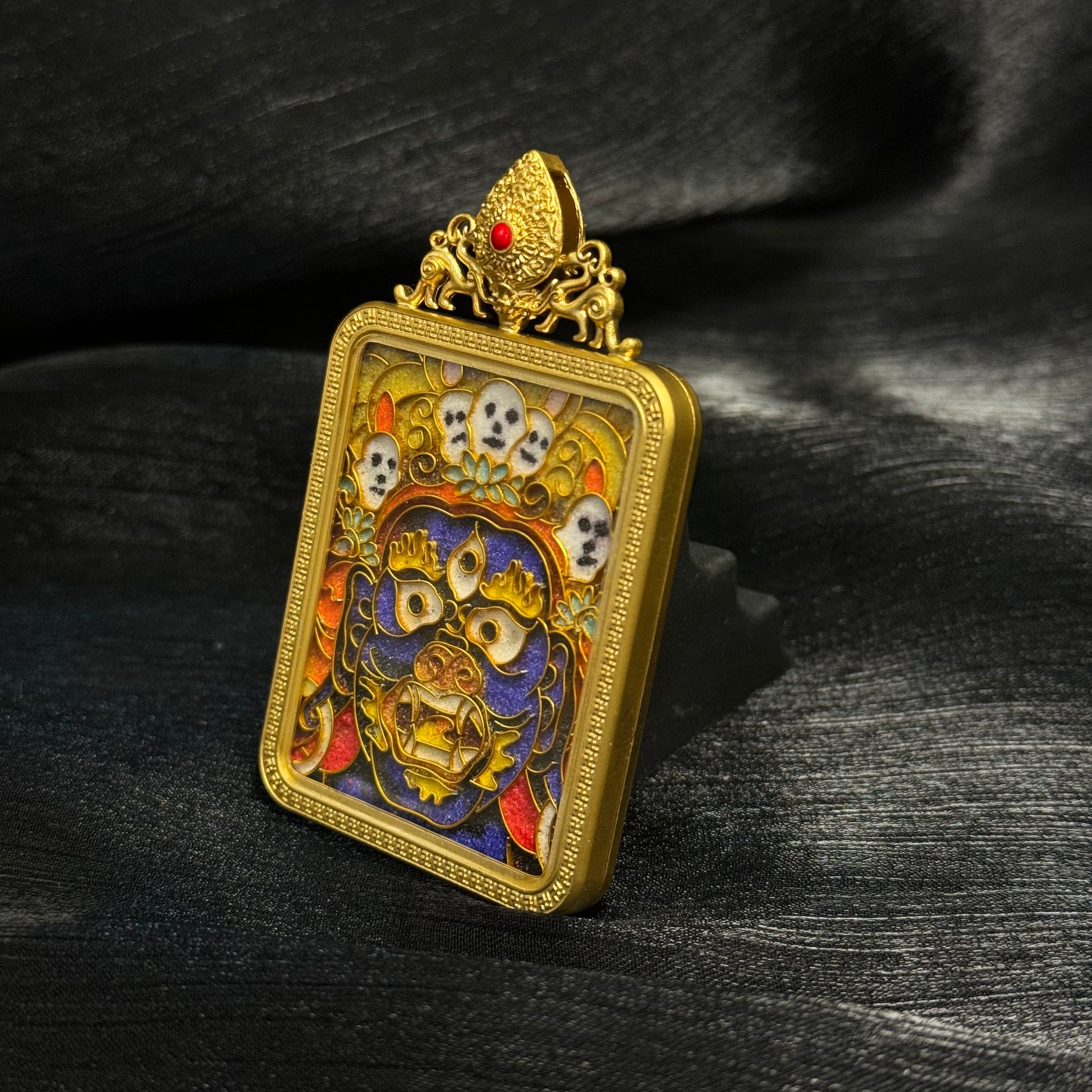 Side-angle detail of a Palden Lhamo cloisonné enamel pendant highlighting the thickness of the gold-plated copper case, framed edges, and intricate enamel deity design.